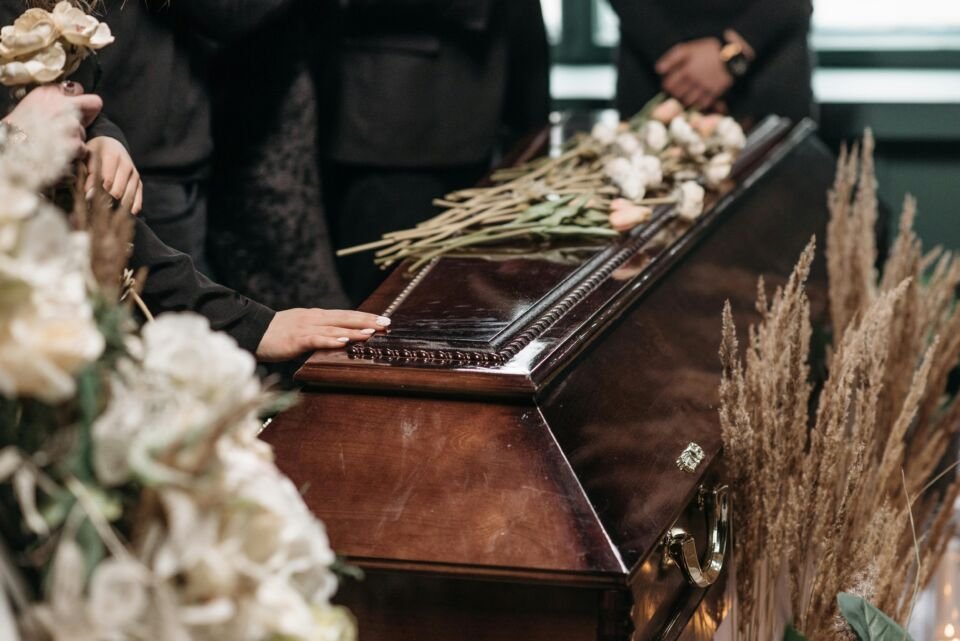 Foto de mãos sobre um caxão durante um velório