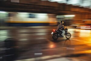 Imagem de motociclista andando com moto na rua a noite