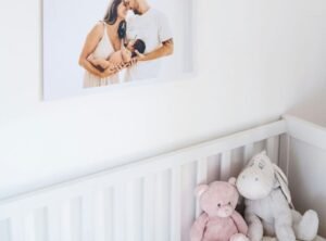 Imagem de quarto de bebê com um berço e a foto de um casal com um recém-nascido no colo