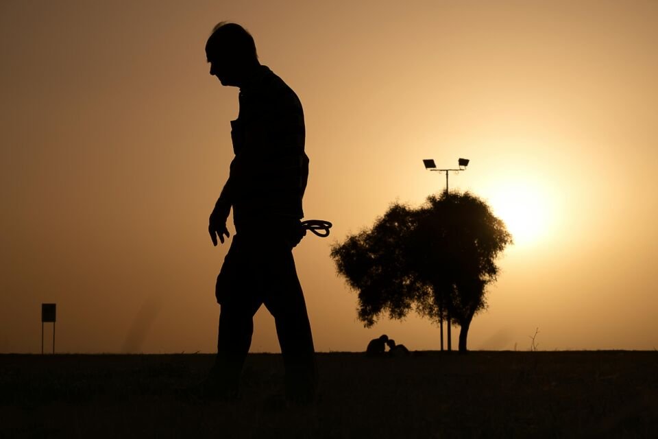 Foto de um idoso caminhando sob um por do Sol